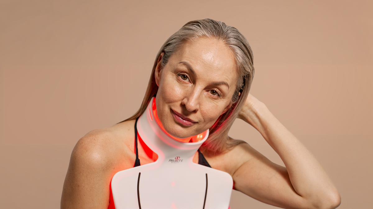 Mature woman wearing LumaLux Face Pro red LED neck device.